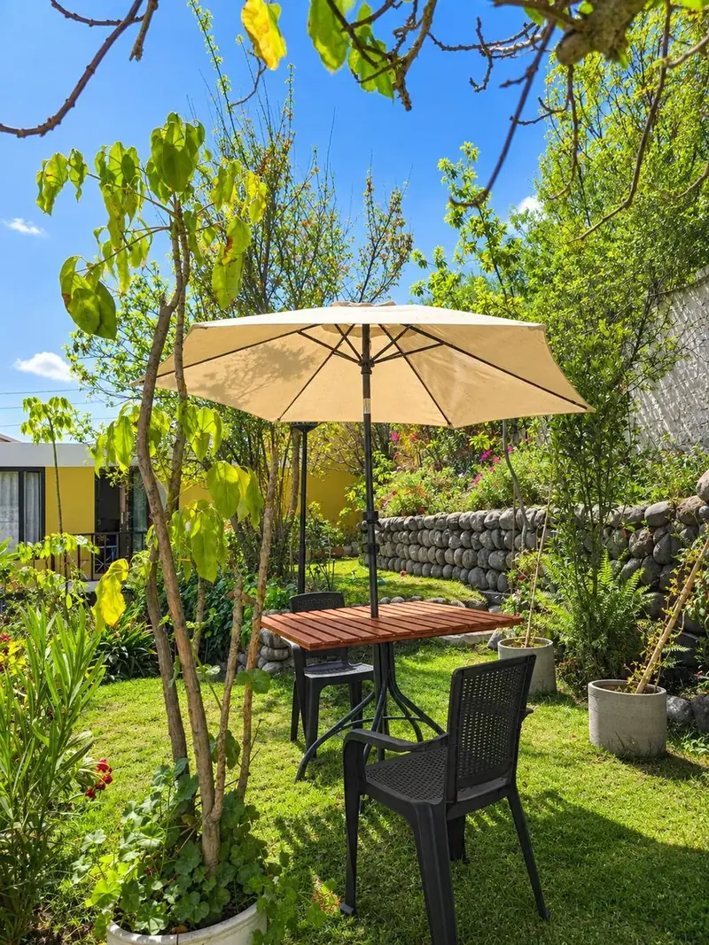 Table under a parasol among the garden’s greenery
